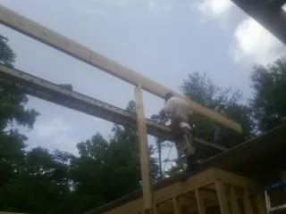 Carpenter setting a ridge beam over a new addition frame — Ice Dam Removal by Roofing Brothers in Superior