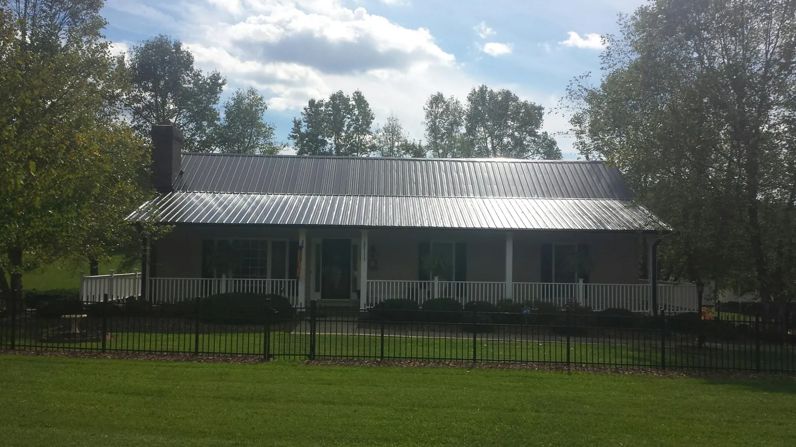 Gray metal roof on a brick ranch with a full width front porch — Gutter Guard Installation work by our crew in Superior